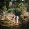 a couple of people walking down a dirt road