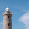 a tall light house sitting on top of a lush green field