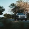 a black truck driving down a street next to trees