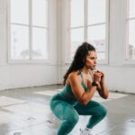 a woman squatting on the floor in a gym