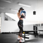 woman in orange and black shirt and black leggings doing exercise